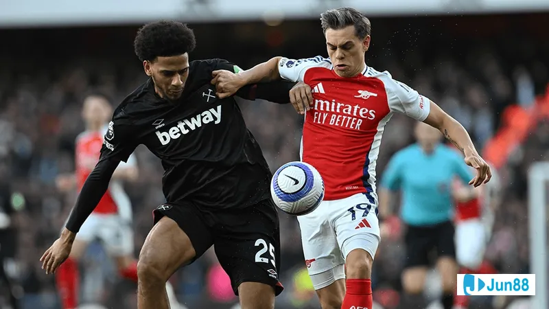 Cầu thủ Arsenal với chiếc áo đỏ và cầu thủ West Ham trong áo màu xanh đang tranh chấp bóng trên sân cỏ Cầu thủ Arsenal với chiếc áo đỏ và cầu thủ West Ham trong áo màu xanh đang tranh chấp bóng…